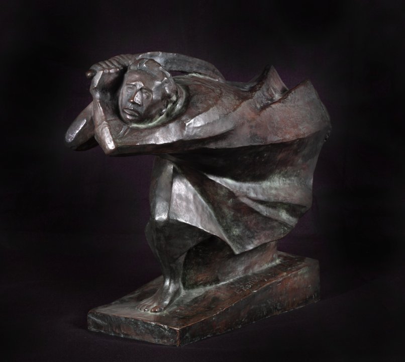 Bronze statue of a man in motion (his cloak blows behind him) as he wields a weapon over his shoulder. The background of the image is black. 