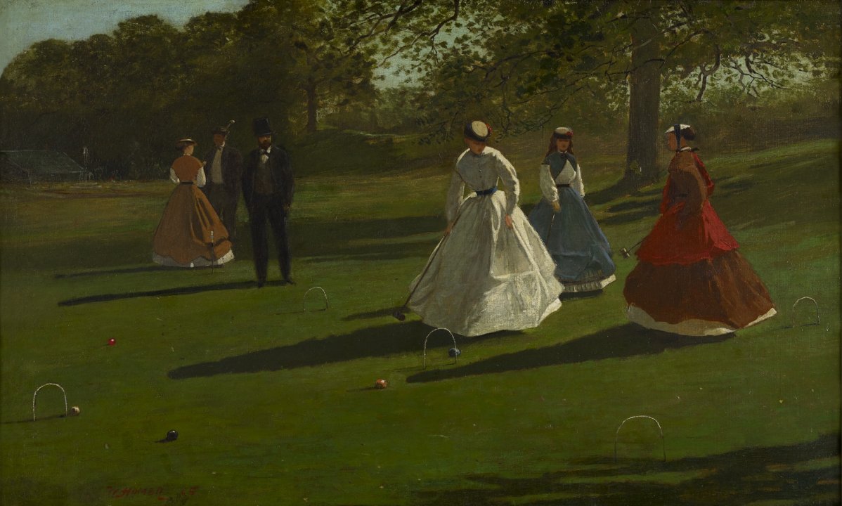 On a patch of grass with trees in the background, a group of four women and two men dressed in victorian style dresses and suits play croquet  