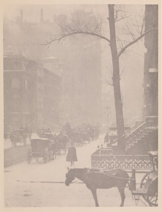 Photogravure of a snowy city street with various horse and buggies throughout