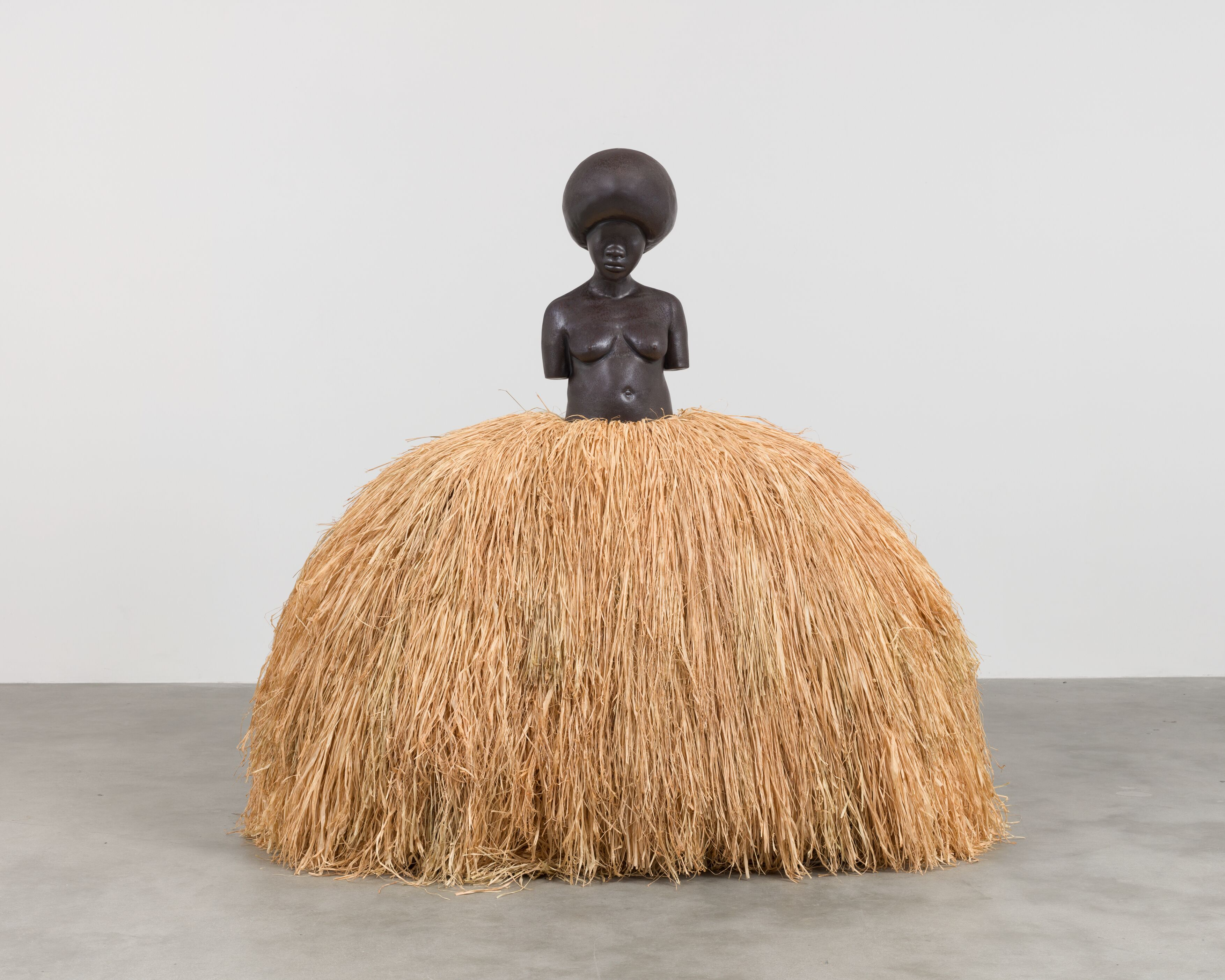 Sculpture of an African woman wearing a large skirt made of hay