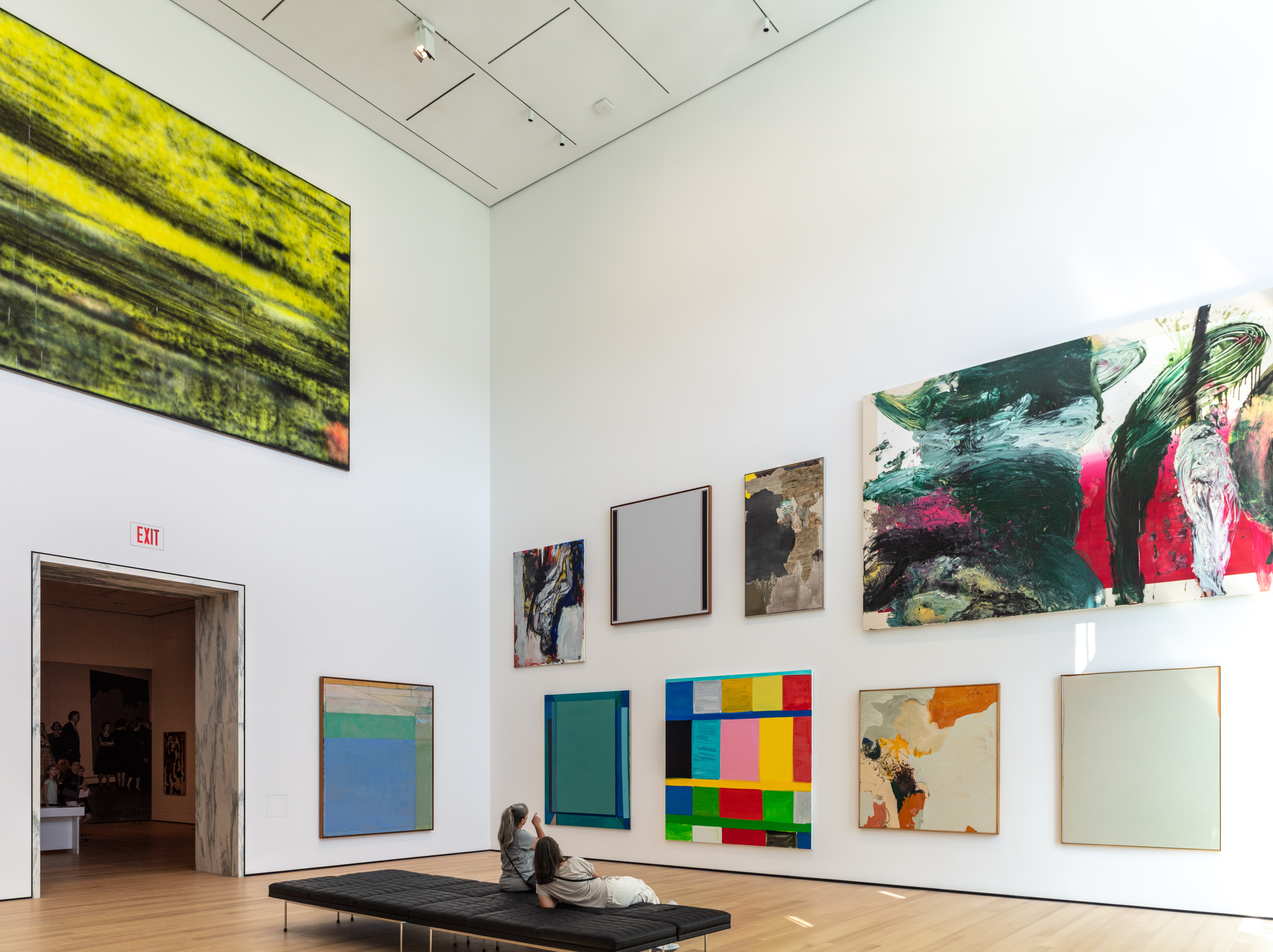 Extremely tall gallery walls with abstract paintings hung up