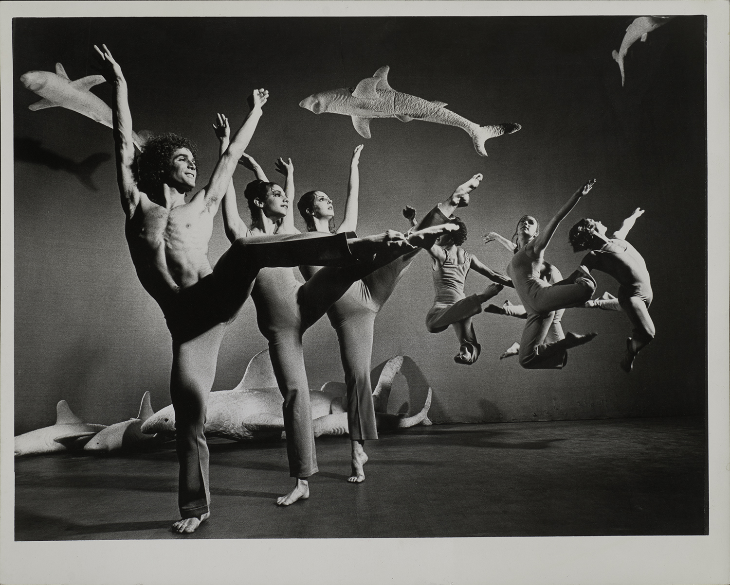 Black and white photo of dancers on a stage with large fish set decorations