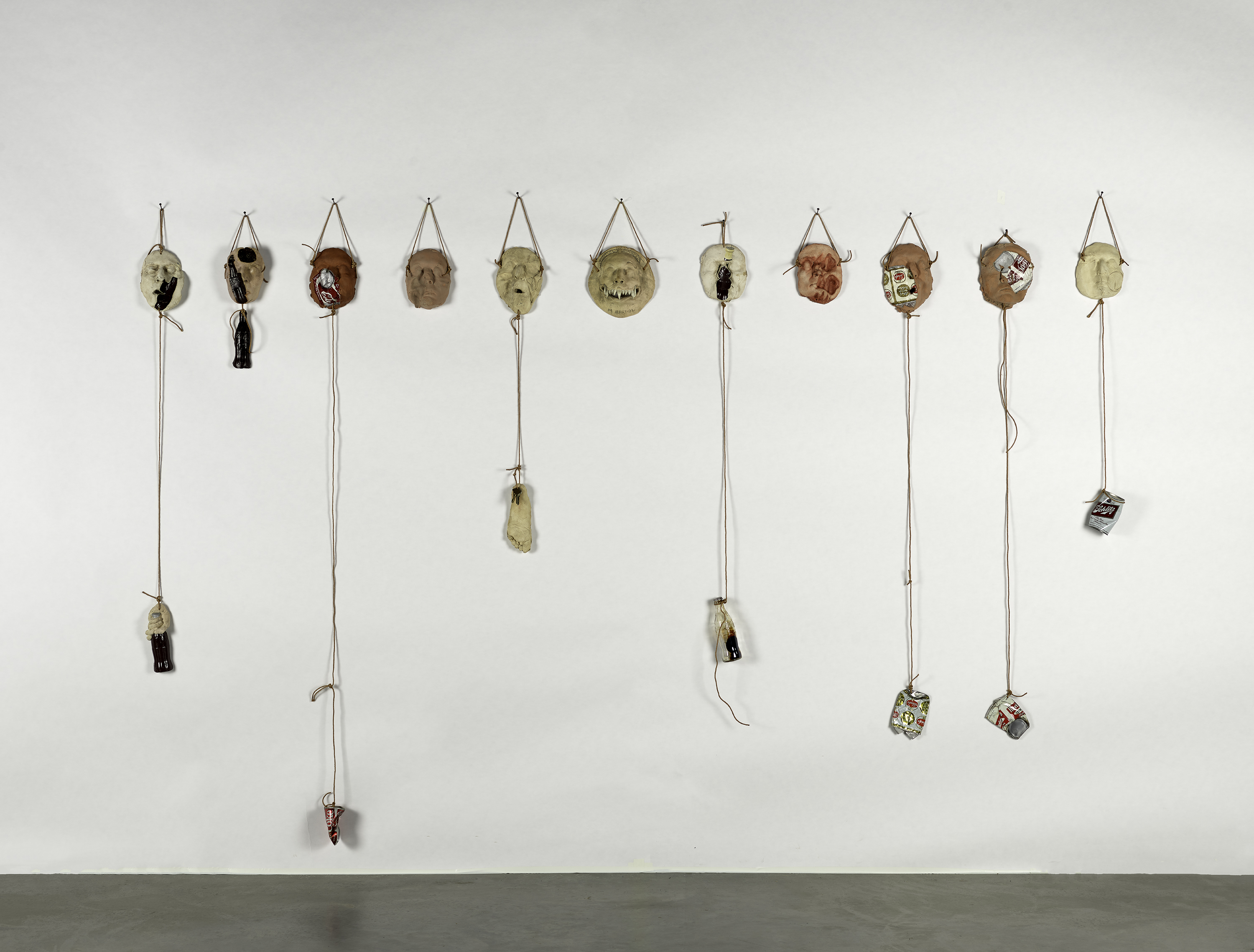 Assorted clay masks hanging on a white wall