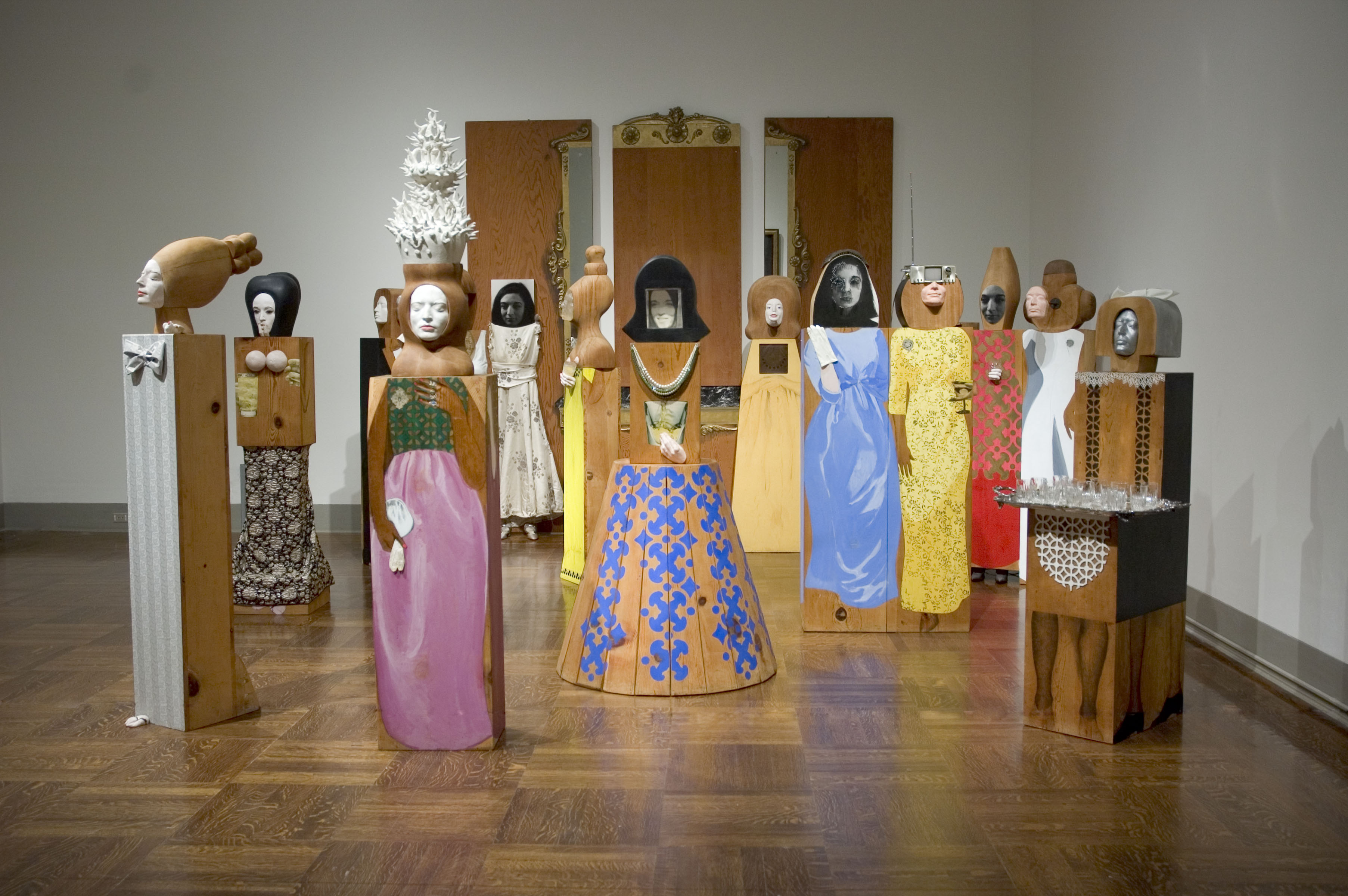 A collection of wooden Pop Art sculptures of people dressed and assembled for a party