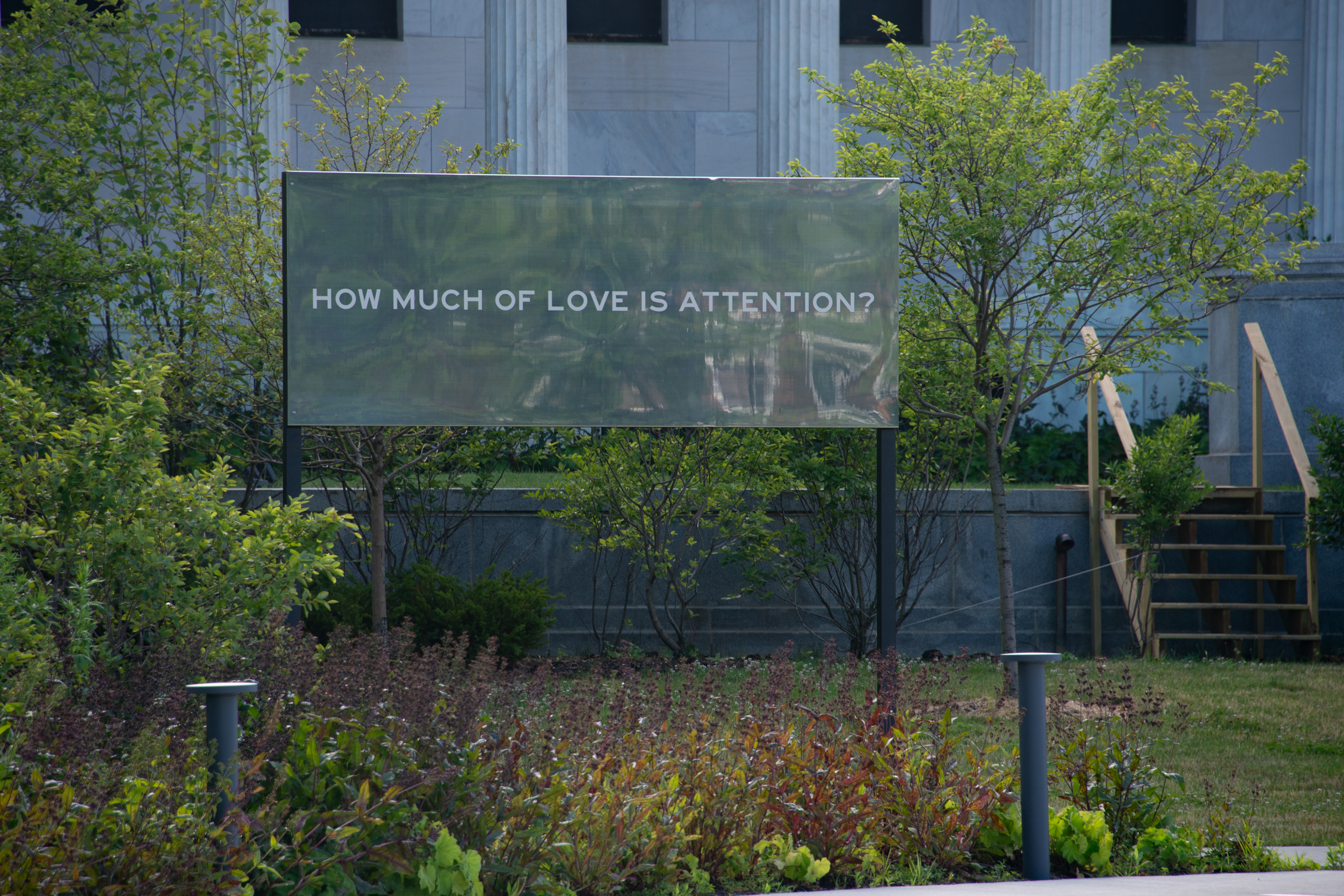 A mirrored billboard that reads "How much of love is attention?"