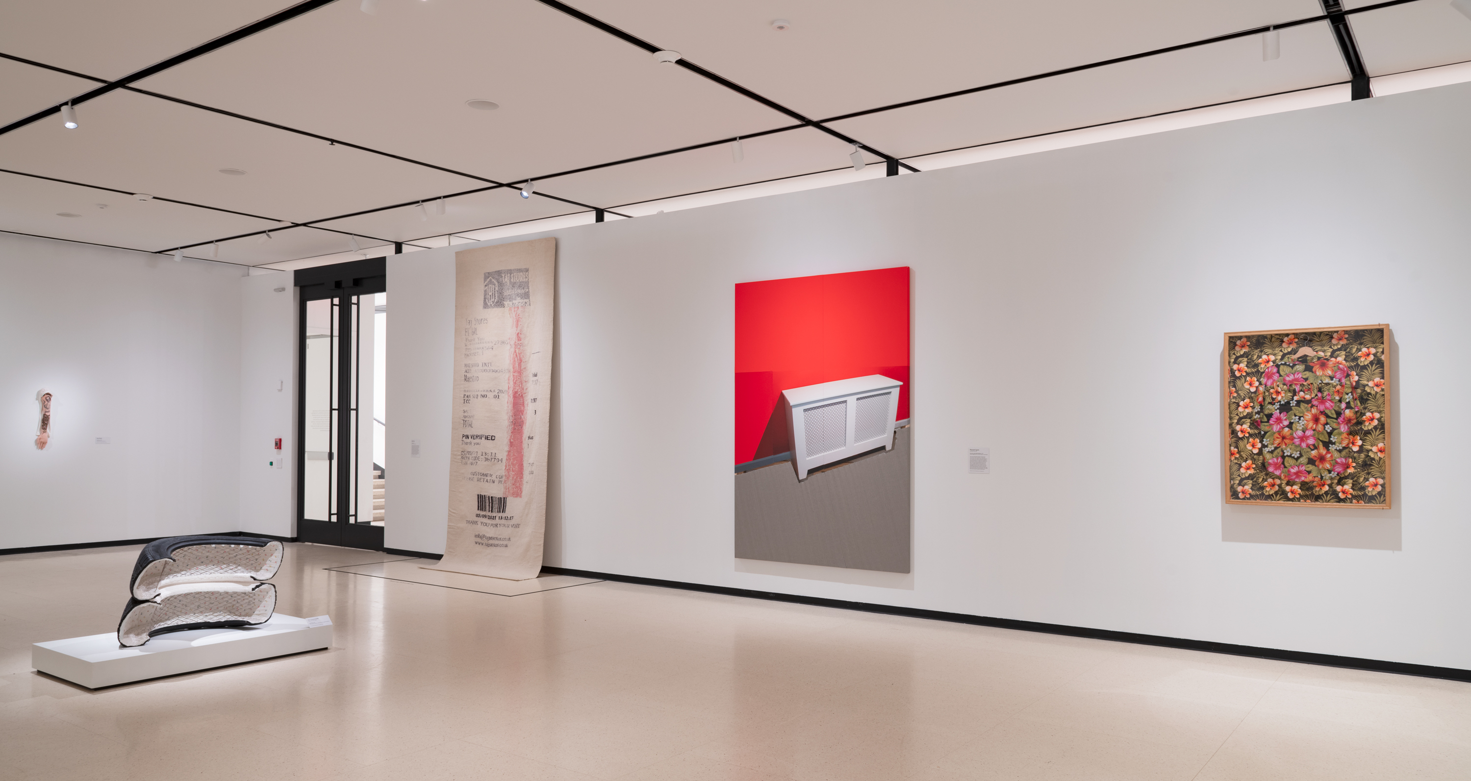 Installation view of three artworks hanging on white walls and a sculpture in the center of the floor