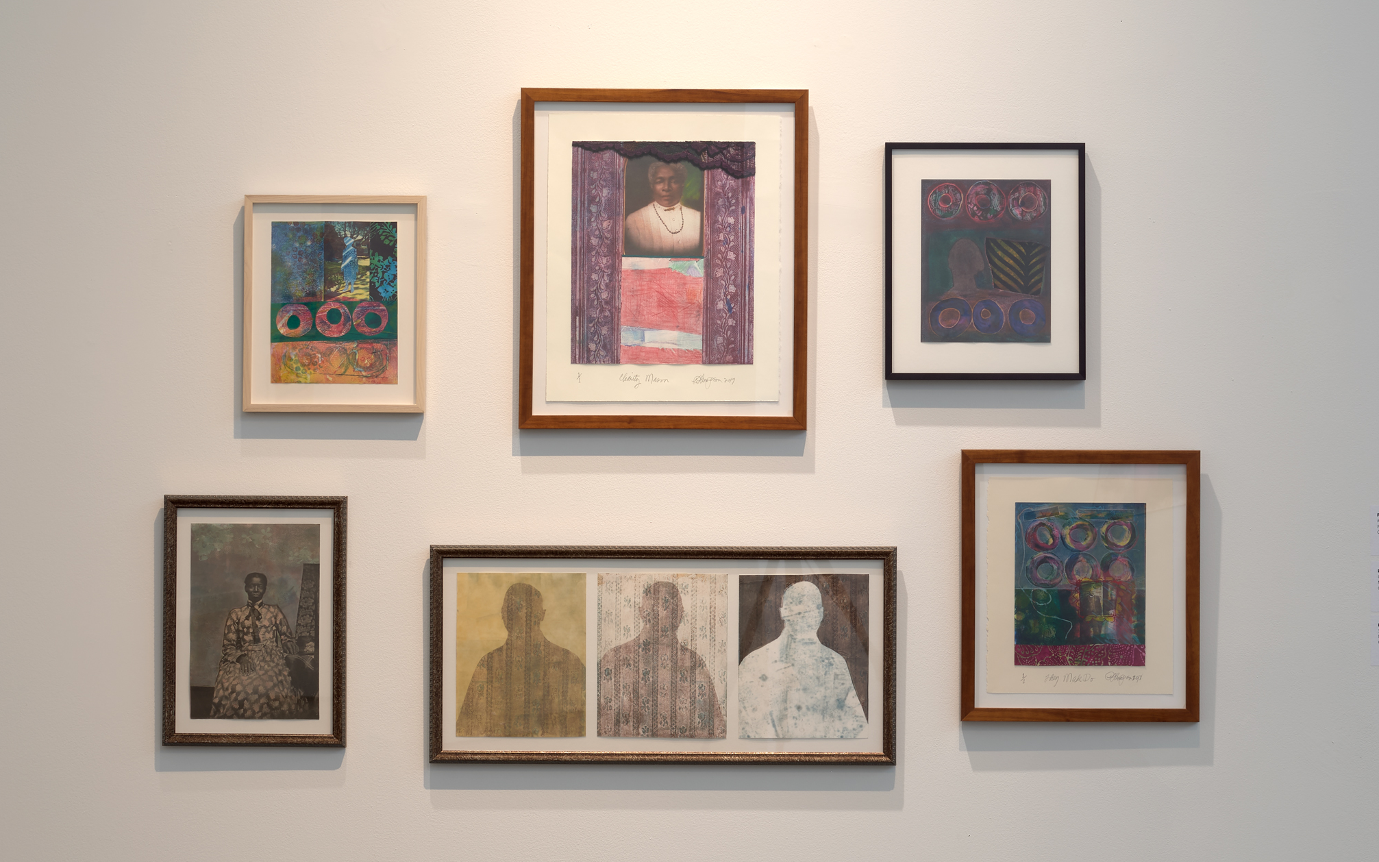Six artworks hung in frames on a white wall showing patterned and colorful prints