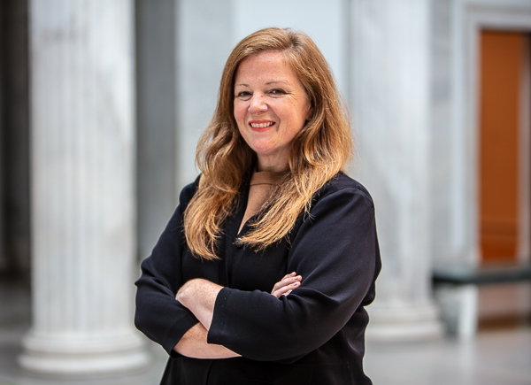 A person smiling with their arms folded