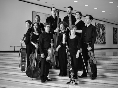 A black and white image of an orchestral group posing together with their instruments