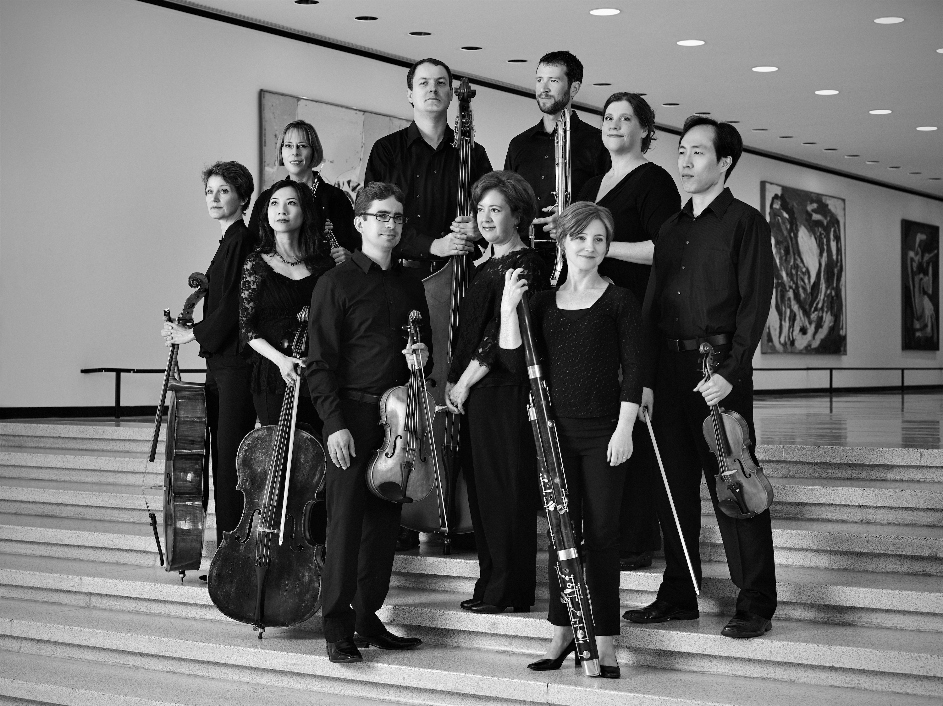Orchestra members posing with their instruments in a black and white photo