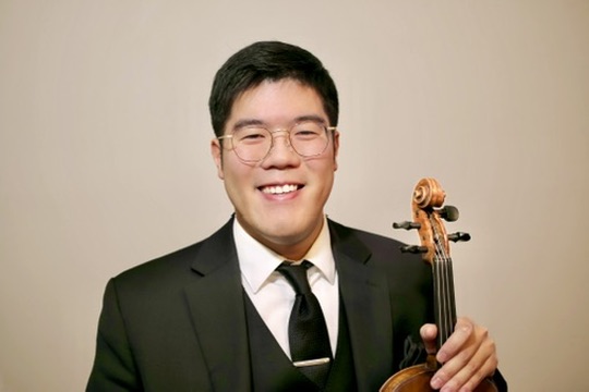 A person wearing a suit and holding a violin