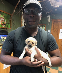 Photo of Famous Clark, wearing a hat and glasses and holding a dog