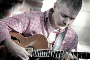 A white man playing the guitar