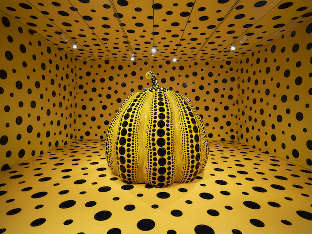A yellow room with black polka dots with a large pumpkin in the center with the same shade of yellow and black polka dots
