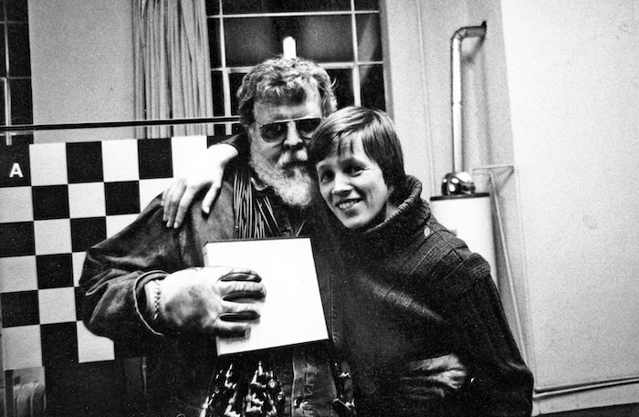 Black and white photo of two people smiling with an arm around one another