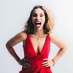 A woman in a red v-neck dress with her hands on her hips and her mouth open wide