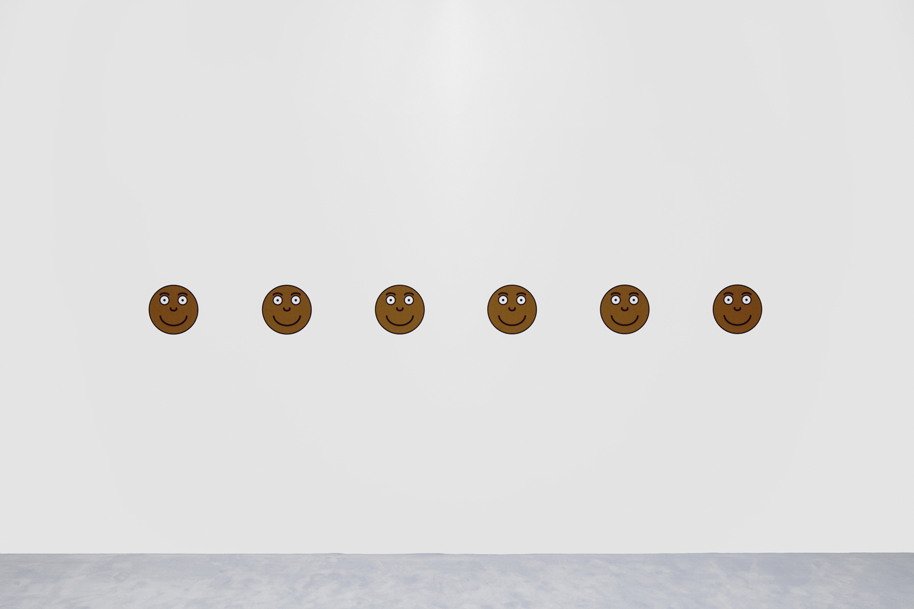 Six smiley faces with mid to dark skin tones lined up on a white wall