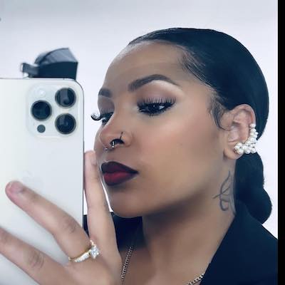 a closeup selfie of a woman with dark hair and red lipstick holding an iphone