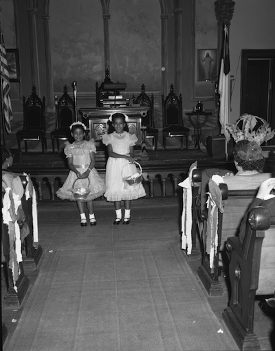 Black and white photo of two flower girls of dark skin tone in a wedding venue