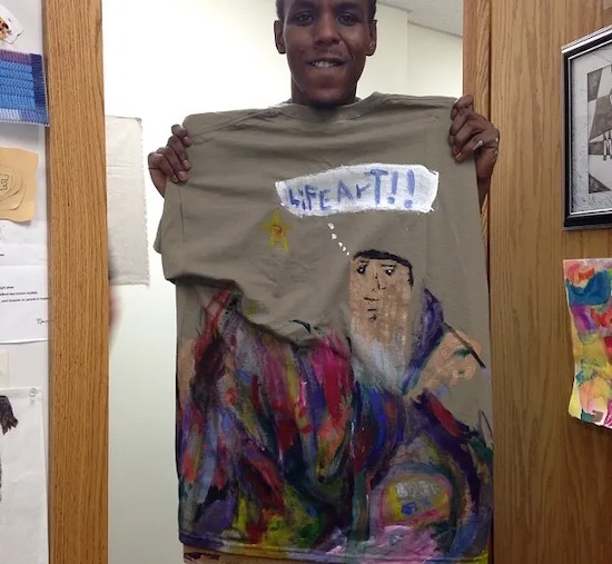 A man smiling while holding up a painting he made