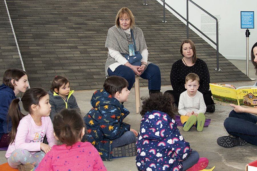 A woman reading a book to a group of children sitting on the floor in front of her