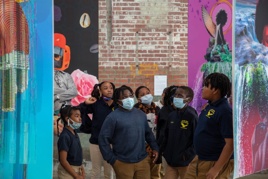 A group of Black children looking at collaged banners hanging from the ceiling