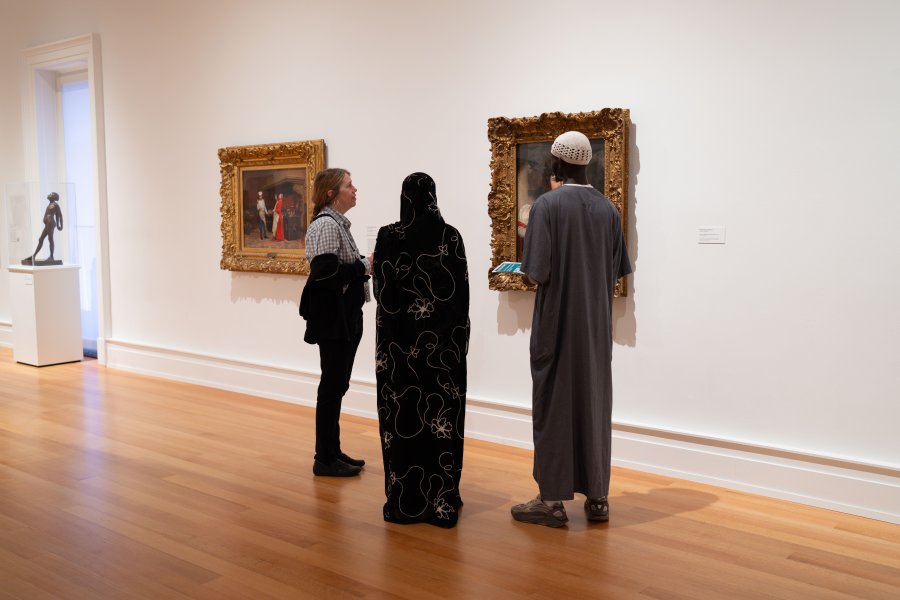 Three people standing in front of a painting