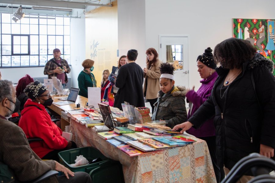 People perusing a table of books with people sitting on the opposite side of the table