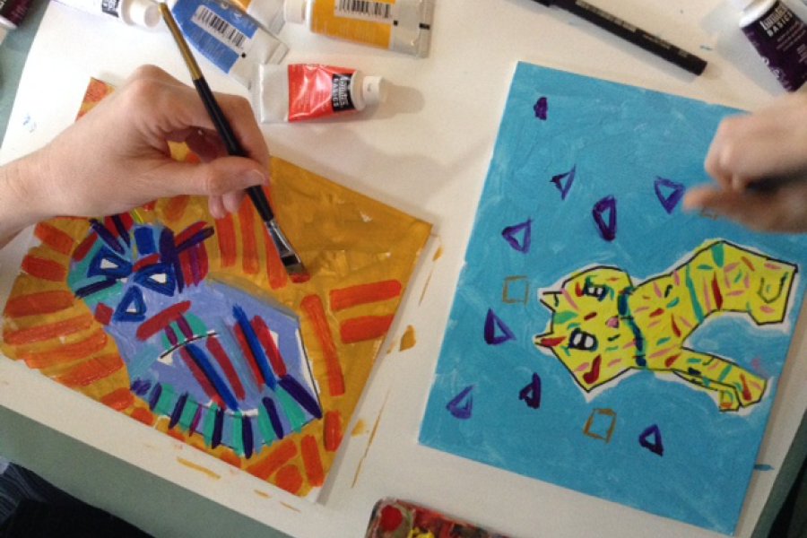 Two people creating colorful paintings of cats