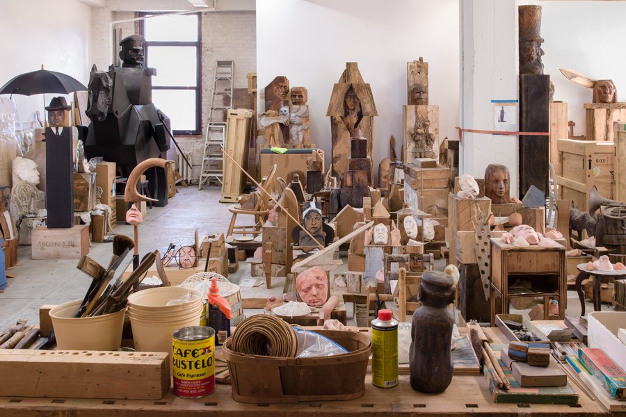 View of Marisol’s New York studio, filled with wooden sculpture pieces and art supplies