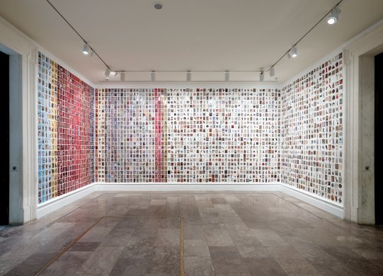 A room with postcards filling three walls from floor to ceiling