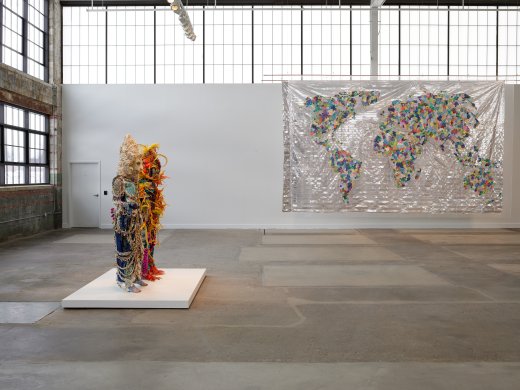 Two human-size costumes and a large map made of colored fabric flowers and beads