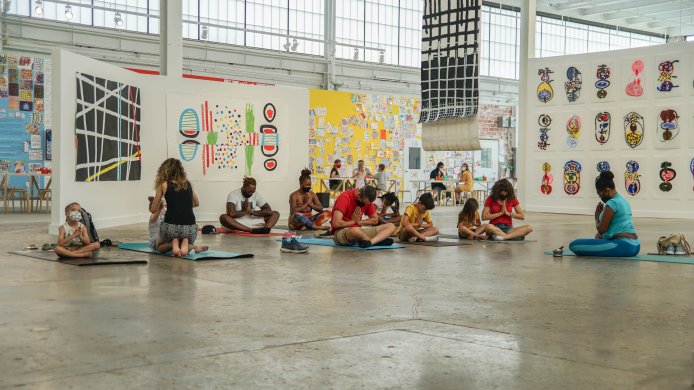 Families do yoga on a concrete floor surrounded by art
