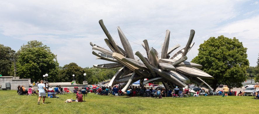 People in lawnchairs outside sitting around a large sculpture