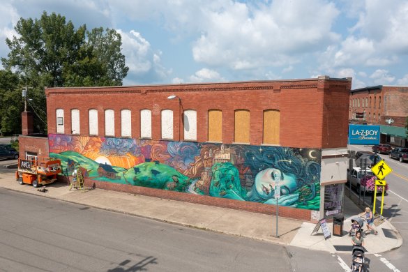 A red brick wall featuring a mural painting of a green sleeping giant