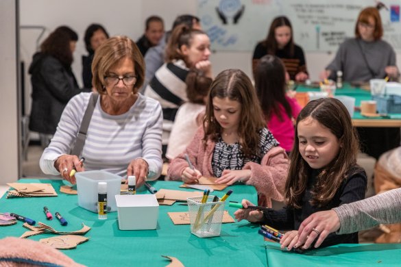 A woman and two young girls working on an art project at a green table