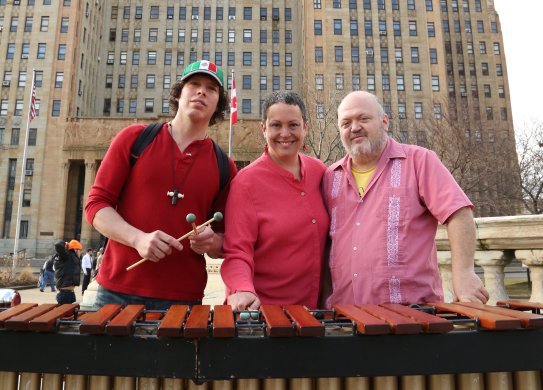 Two men and a woman standing in front of a large brown building