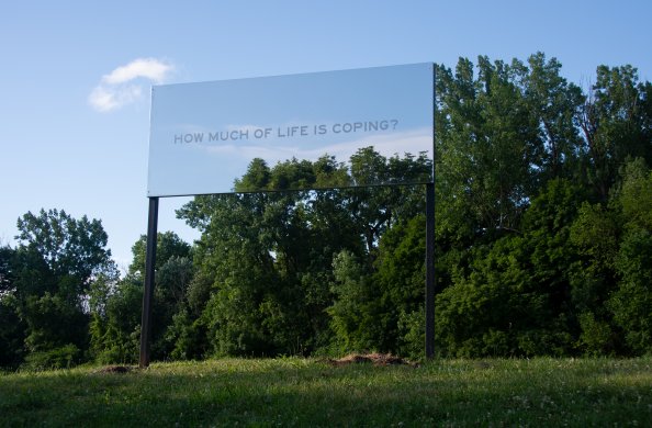 A large mirrored billboard sign in a park that says "How much of life is coping?" 