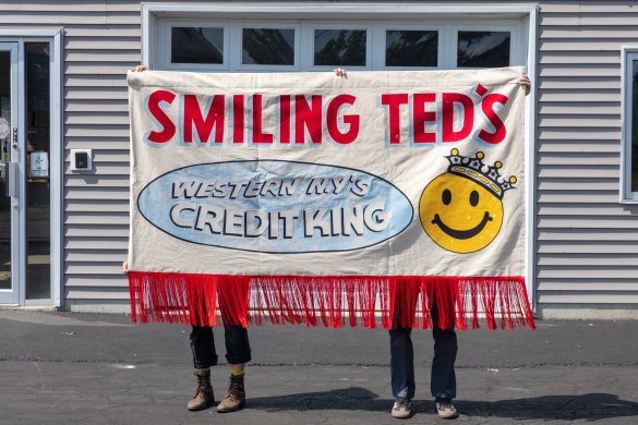 Two people holding up a sign that reads "Smiling Teds" 