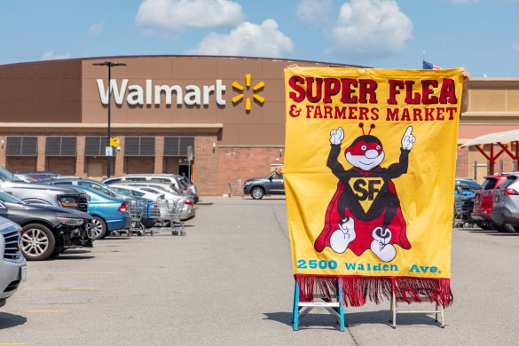 People holding up a vintage sign on fabric in front of Walmart