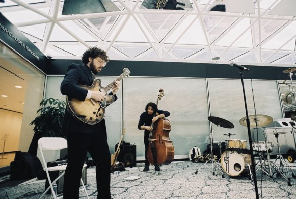 Two guitarists performing under a glass mosaic ceiling