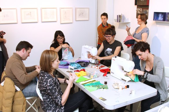 A group of people working on a sewing project in a gallery space