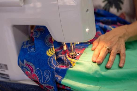 Hands working at a sewing machine on vibrant colored fabrics
