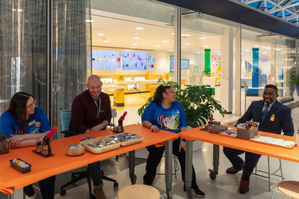 People sitting at a table with button-making supplies