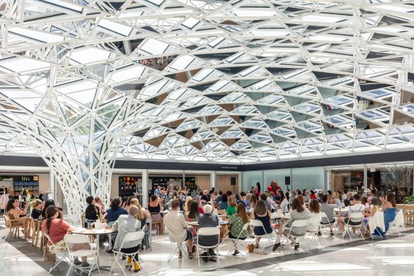 People gathered at tables under a glass mosaic ceiling 
