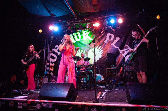 A band performing on a stage surrounded by neon lights