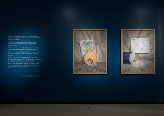 Installation view of a vinyl wall text treatment and two oil painting still lifes to the right of it