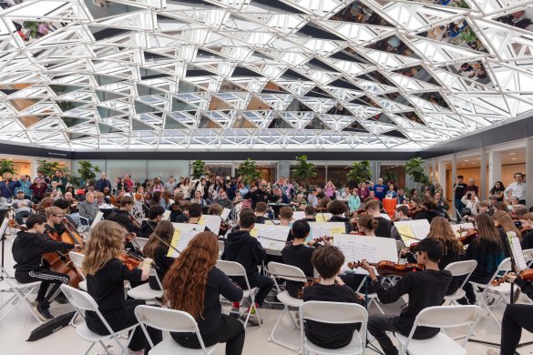 A student orchestra performing under a glass mosaic ceiling