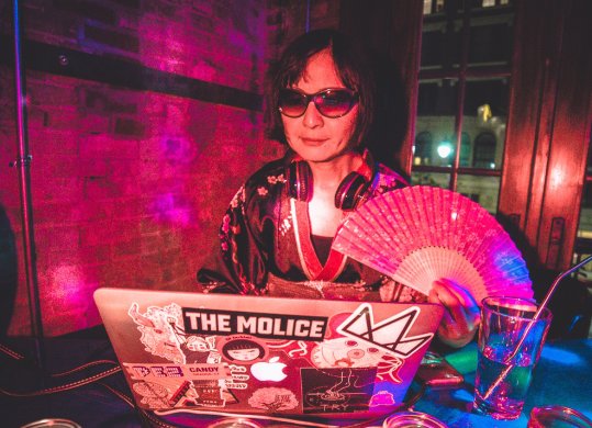 A person wearing sunglasses in front of a laptop computer