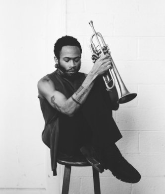 Black and white image of a person sitting on a stool with a trumpet
